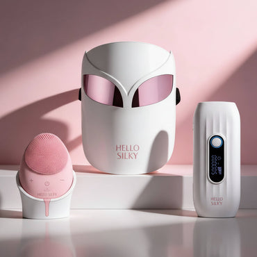 Three skincare devices from the brand 'HELLO SILKY' on a pink background